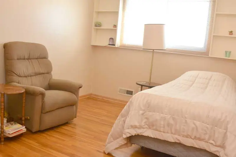 Bedroom with purple bedding and recliner