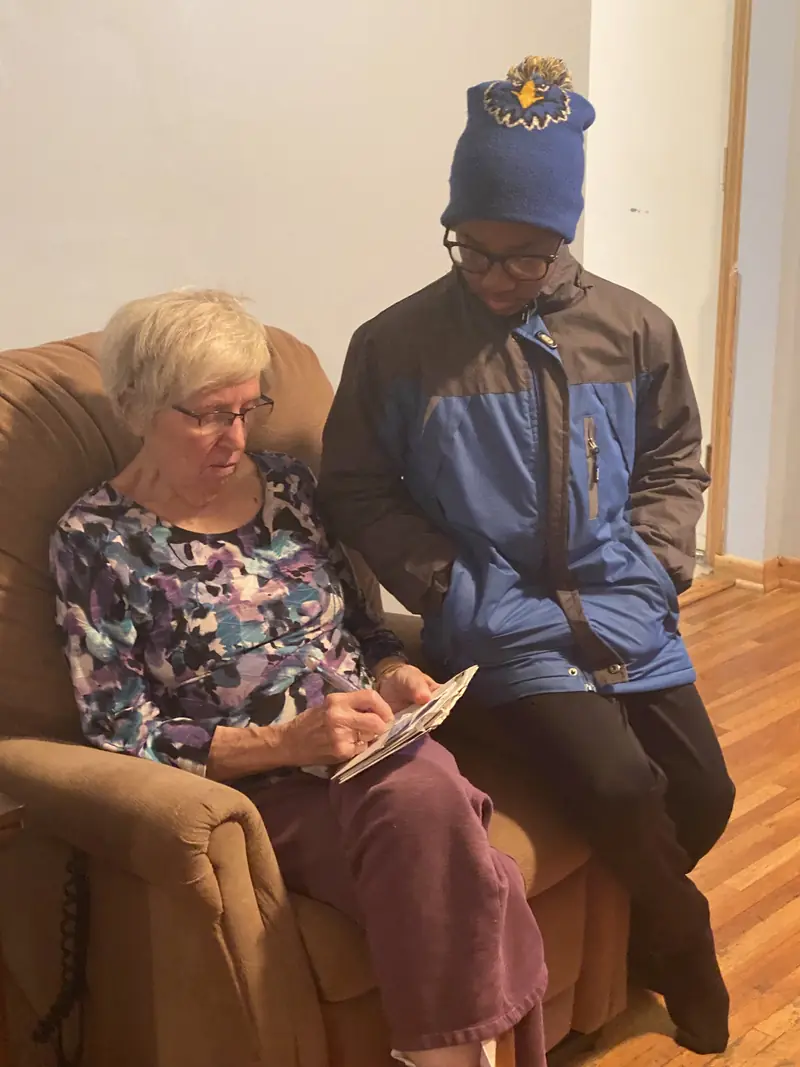 Resident working on a crossword with a young visitor